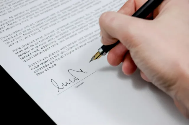 Free hand holding pen signing. Content marketing agency contract terms: what UK clients must check